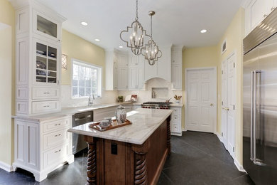 Cette photo montre une cuisine chic avec des portes de placard blanches, un plan de travail en quartz et un sol noir.