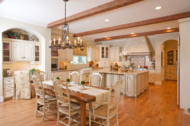 Large french country u-shaped medium tone wood floor eat-in kitchen photo in Houston with raised-panel cabinets, beige cabinets, a farmhouse sink, granite countertops, beige backsplash, ceramic backsplash, stainless steel appliances and an island