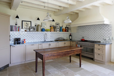 Inredning av ett lantligt avskilt, stort l-kök, med en integrerad diskho, luckor med infälld panel, beige skåp, vitt stänkskydd, stänkskydd i tunnelbanekakel, integrerade vitvaror och en köksö