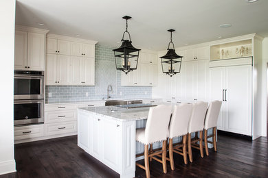 Large elegant l-shaped dark wood floor and brown floor eat-in kitchen photo in Indianapolis with an undermount sink, raised-panel cabinets, white cabinets, granite countertops, blue backsplash, ceramic backsplash, paneled appliances, an island and gray countertops