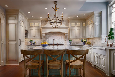 Large french country u-shaped dark wood floor enclosed kitchen photo in Chicago with a farmhouse sink, raised-panel cabinets, beige cabinets, white backsplash, paneled appliances, an island, quartz countertops and glass tile backsplash