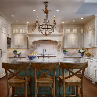 Foto di una grande cucina ad U chiusa con lavello stile country, ante con bugna sagomata, ante beige, paraspruzzi bianco, elettrodomestici da incasso, parquet scuro, isola, top in quarzo composito e paraspruzzi con piastrelle di vetro
