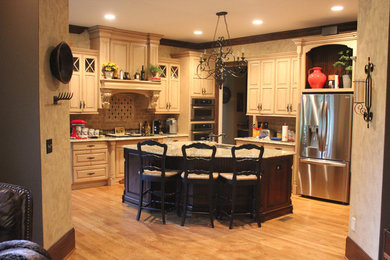 Exempel på ett avskilt, stort klassiskt kök, med luckor med upphöjd panel, beige skåp, stänkskydd i keramik, rostfria vitvaror, mellanmörkt trägolv och en köksö