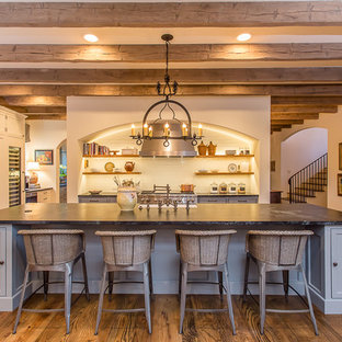 Foto di una grande cucina mediterranea con lavello stile country, ante a filo, ante blu, top in saponaria, paraspruzzi bianco, paraspruzzi con piastrelle diamantate, elettrodomestici da incasso, parquet scuro e isola