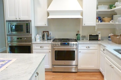 ワシントンD.C.にある高級な中くらいなトラディショナルスタイルのおしゃれなキッチン (アンダーカウンターシンク、落し込みパネル扉のキャビネット、白いキャビネット、大理石カウンター、シルバーの調理設備、淡色無垢フローリング、ベージュの床) の写真