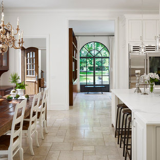 Design ideas for a traditional u-shaped eat-in kitchen in Chicago with a single-bowl sink, white cabinets, marble benchtops, white splashback, stone slab splashback, stainless steel appliances, travertine floors and with island.