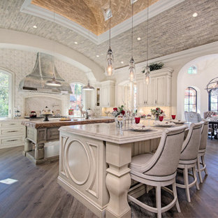 Ispirazione per un'ampia cucina ad U stile shabby chiusa con lavello stile country, ante con bugna sagomata, ante in legno chiaro, top in quarzite, paraspruzzi multicolore, paraspruzzi in gres porcellanato, elettrodomestici in acciaio inossidabile, parquet scuro, 2 o più isole, pavimento marrone e top beige