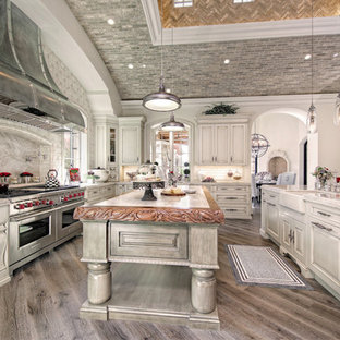 Immagine di un'ampia cucina ad U shabby-chic style chiusa con lavello stile country, ante con riquadro incassato, ante in legno chiaro, top in quarzite, paraspruzzi multicolore, paraspruzzi in marmo, elettrodomestici in acciaio inossidabile, pavimento in legno massello medio, 2 o più isole, pavimento marrone e top multicolore