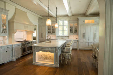 Inredning av ett klassiskt stort kök och matrum, med en rustik diskho, luckor med upphöjd panel, beige skåp, marmorbänkskiva, vitt stänkskydd, en köksö, integrerade vitvaror, mellanmörkt trägolv och stänkskydd i keramik