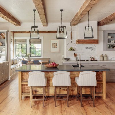 Cottage u-shaped medium tone wood floor and brown floor kitchen photo in Boston with a farmhouse sink, shaker cabinets, gray cabinets, white backsplash, stone slab backsplash, paneled appliances, an island and white countertops