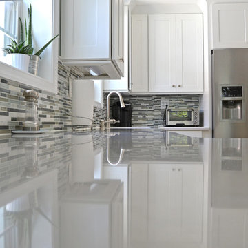 Fresh kitchen makeover with white shaker cabinets, tile backsplash, and pendants