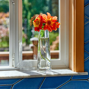 Mid-sized u-shaped eat-in kitchen in Other with an integrated sink, shaker cabinets, light wood cabinets, stainless steel benchtops, blue splashback, ceramic splashback, stainless steel appliances, linoleum floors, a peninsula and brown floor.