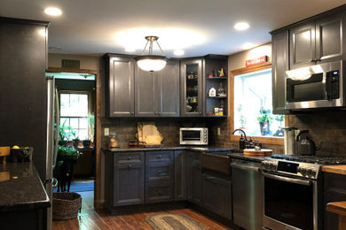Inspiration for a mid-sized timeless galley dark wood floor and brown floor eat-in kitchen remodel in Bridgeport with a farmhouse sink, raised-panel cabinets, brown cabinets, granite countertops, brown backsplash, stone tile backsplash, stainless steel appliances, no island and brown countertops