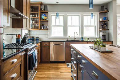 Mid-sized transitional l-shaped medium tone wood floor eat-in kitchen photo in Minneapolis with an undermount sink, shaker cabinets, medium tone wood cabinets, granite countertops, white backsplash, ceramic backsplash, stainless steel appliances and an island