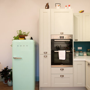 Esempio di una cucina minimal di medie dimensioni con lavello a doppia vasca, ante in stile shaker, ante verdi, top in superficie solida, paraspruzzi bianco, elettrodomestici da incasso, parquet chiaro e nessuna isola