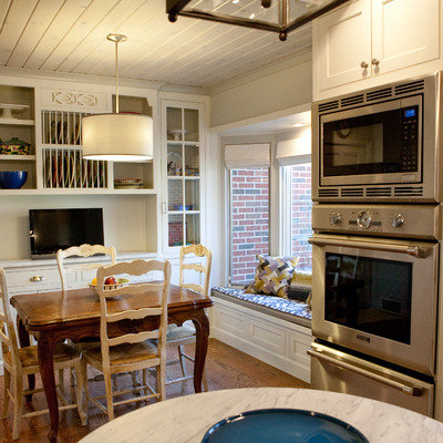 Elegant galley eat-in kitchen photo in Other with glass-front cabinets, white cabinets, white backsplash, stone tile backsplash and stainless steel appliances