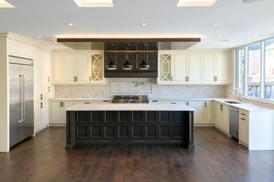 Example of a transitional u-shaped dark wood floor and brown floor open concept kitchen design in Toronto with an undermount sink, shaker cabinets, beige cabinets, quartz countertops, gray backsplash, marble backsplash, stainless steel appliances and an island
