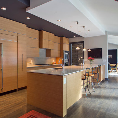 Example of a mid-sized minimalist galley medium tone wood floor and brown floor eat-in kitchen design in Atlanta with flat-panel cabinets, medium tone wood cabinets, gray backsplash, paneled appliances, a single-bowl sink, ceramic backsplash, a peninsula and quartzite countertops