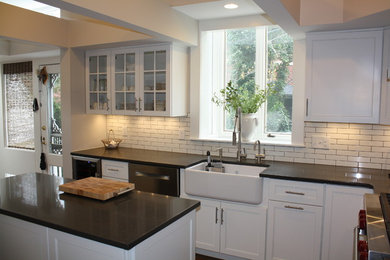 Eat-in kitchen - mid-sized transitional l-shaped dark wood floor eat-in kitchen idea in DC Metro with a farmhouse sink, recessed-panel cabinets, white cabinets, quartz countertops, white backsplash, ceramic backsplash, stainless steel appliances and an island