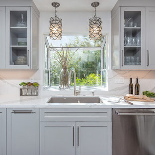 Esempio di una cucina abitabile moderna di medie dimensioni con lavello sottopiano, ante bianche, top in quarzo composito, paraspruzzi bianco, paraspruzzi con piastrelle di vetro, elettrodomestici in acciaio inossidabile, pavimento in legno massello medio, nessuna isola, pavimento marrone e top bianco
