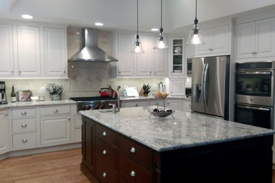 Inspiration for a large transitional u-shaped medium tone wood floor eat-in kitchen remodel in Chicago with a farmhouse sink, beaded inset cabinets, white cabinets, granite countertops, gray backsplash, subway tile backsplash, stainless steel appliances and an island