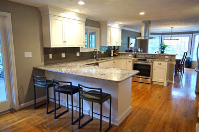 Inspiration for a mid-sized timeless u-shaped medium tone wood floor eat-in kitchen remodel in Boston with an undermount sink, beaded inset cabinets, white cabinets, granite countertops, gray backsplash, glass tile backsplash, stainless steel appliances and a peninsula