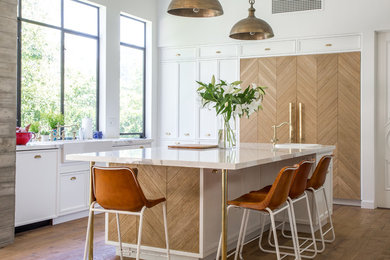 Inspiration for a transitional light wood floor kitchen remodel in Los Angeles with a farmhouse sink, recessed-panel cabinets, white cabinets, paneled appliances and an island