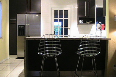 Eat-in kitchen - mid-sized contemporary u-shaped ceramic tile eat-in kitchen idea in Miami with flat-panel cabinets, black cabinets, granite countertops, white backsplash, subway tile backsplash, stainless steel appliances and a peninsula