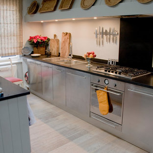This is an example of a small modern galley separate kitchen in London with flat-panel cabinets, stainless steel cabinets, marble benchtops, black splashback, ceramic splashback, light hardwood floors and no island.
