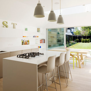 Idee per una cucina design di medie dimensioni con ante lisce, top in superficie solida, paraspruzzi bianco, isola, lavello sottopiano, ante beige, parquet chiaro, paraspruzzi con lastra di vetro, elettrodomestici in acciaio inossidabile, pavimento beige e top beige