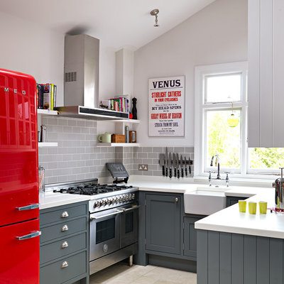 Small elegant u-shaped ceramic tile and beige floor enclosed kitchen photo in London with a farmhouse sink, shaker cabinets, gray cabinets, gray backsplash, subway tile backsplash, no island, solid surface countertops and stainless steel appliances