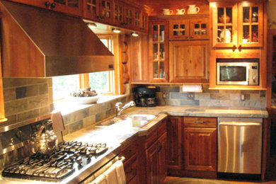 オースティンにある中くらいなラスティックスタイルのおしゃれなキッチン (ダブルシンク、レイズドパネル扉のキャビネット、濃色木目調キャビネット、タイルカウンター、マルチカラーのキッチンパネル、スレートのキッチンパネル、シルバーの調理設備、テラコッタタイルの床、アイランドなし、オレンジの床、マルチカラーのキッチンカウンター) の写真