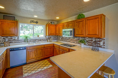 Example of a southwest u-shaped brick floor kitchen design in Albuquerque with a double-bowl sink, raised-panel cabinets, multicolored backsplash, matchstick tile backsplash and a peninsula