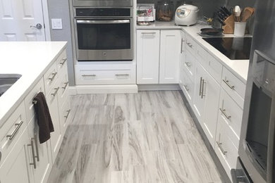Inspiration for a mid-sized modern l-shaped porcelain tile eat-in kitchen remodel in Orlando with shaker cabinets, white cabinets, solid surface countertops, an island, an undermount sink and stainless steel appliances