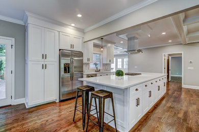 Transitional l-shaped medium tone wood floor open concept kitchen photo in Atlanta with a double-bowl sink, shaker cabinets, white cabinets, quartz countertops, gray backsplash, marble backsplash, stainless steel appliances, an island and white countertops