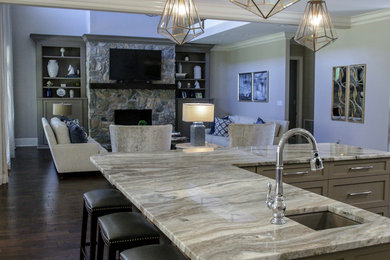Example of a large transitional galley medium tone wood floor and brown floor open concept kitchen design in Atlanta with a single-bowl sink, shaker cabinets, beige cabinets, solid surface countertops, multicolored backsplash, porcelain backsplash, stainless steel appliances, an island and black countertops