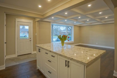 Cette image montre une cuisine traditionnelle avec un placard à porte shaker, un plan de travail en granite, une crédence blanche, une crédence en céramique et un sol en bois brun.