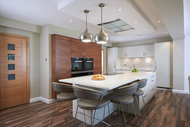 Design ideas for a large contemporary u-shaped open plan kitchen in Manchester with flat-panel cabinets, medium wood cabinets, white splashback, an island, brown floors, quartz worktops, stainless steel appliances and vinyl flooring.
