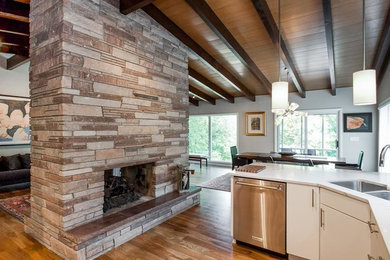 Example of a mid-sized mid-century modern u-shaped medium tone wood floor and brown floor open concept kitchen design in Cedar Rapids with an undermount sink, flat-panel cabinets, white cabinets, quartzite countertops, white backsplash, subway tile backsplash and stainless steel appliances