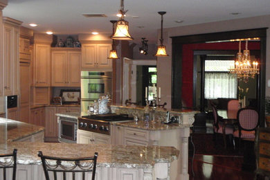 This is an example of a medium sized traditional u-shaped kitchen/diner in Denver with raised-panel cabinets, white cabinets, granite worktops, stainless steel appliances, medium hardwood flooring, an island, brown floors and grey worktops.