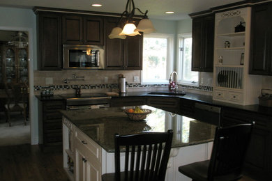 Large classic u-shaped kitchen/diner in Denver with a submerged sink, beaded cabinets, dark wood cabinets, composite countertops, black splashback, metro tiled splashback, stainless steel appliances, medium hardwood flooring and an island.