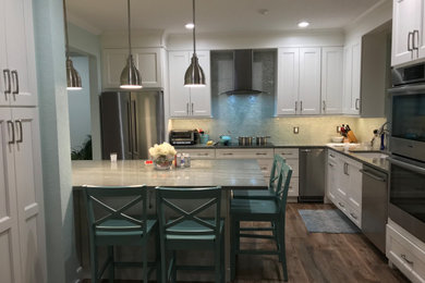 Example of a large transitional porcelain tile and brown floor open concept kitchen design in Miami with an undermount sink, shaker cabinets, white cabinets, granite countertops, blue backsplash, glass tile backsplash, stainless steel appliances, an island and multicolored countertops