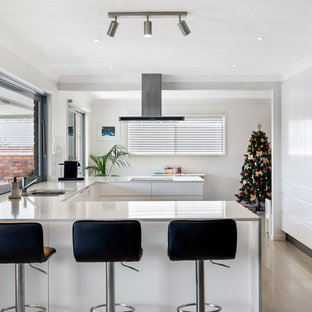 Photo of a mid-sized contemporary u-shaped eat-in kitchen in Gold Coast - Tweed with flat-panel cabinets, white cabinets, quartz benchtops, white splashback, subway tile splashback, white benchtop, a double-bowl sink, stainless steel appliances, a peninsula and beige floor.