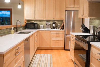 Example of a mid-sized transitional u-shaped light wood floor enclosed kitchen design in Vancouver with an undermount sink, shaker cabinets, light wood cabinets, quartz countertops, green backsplash, subway tile backsplash, stainless steel appliances and no island