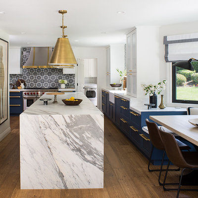 Example of a large transitional u-shaped medium tone wood floor and brown floor eat-in kitchen design in Los Angeles with a farmhouse sink, shaker cabinets, blue cabinets, multicolored backsplash, paneled appliances, an island, gray countertops, marble countertops and ceramic backsplash