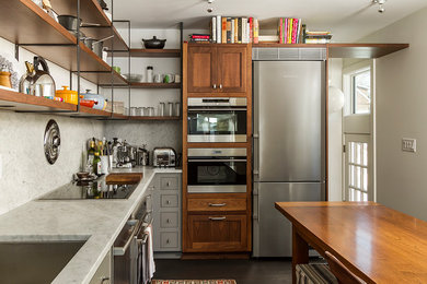 Modelo de cocina ecléctica con fregadero bajoencimera, encimera de mármol, salpicadero de mármol, electrodomésticos de acero inoxidable, suelo de madera oscura, salpicadero blanco, encimeras blancas y puertas de armario de madera en tonos medios