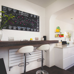 Design ideas for a small contemporary kitchen in Cornwall with a submerged sink, flat-panel cabinets, white cabinets, black floors and white worktops.