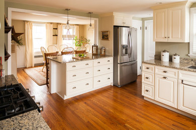 Example of a mid-sized classic u-shaped medium tone wood floor eat-in kitchen design in New York with an undermount sink, raised-panel cabinets, white cabinets, granite countertops, stainless steel appliances and a peninsula