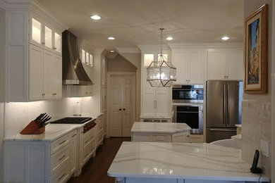 Inspiration for a large transitional single-wall dark wood floor and brown floor enclosed kitchen remodel in Nashville with a farmhouse sink, recessed-panel cabinets, white cabinets, quartzite countertops, white backsplash, subway tile backsplash, stainless steel appliances, an island and white countertops