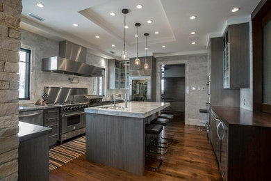 Example of a mid-sized trendy u-shaped medium tone wood floor open concept kitchen design in Salt Lake City with flat-panel cabinets, gray cabinets, marble countertops, stainless steel appliances and an island